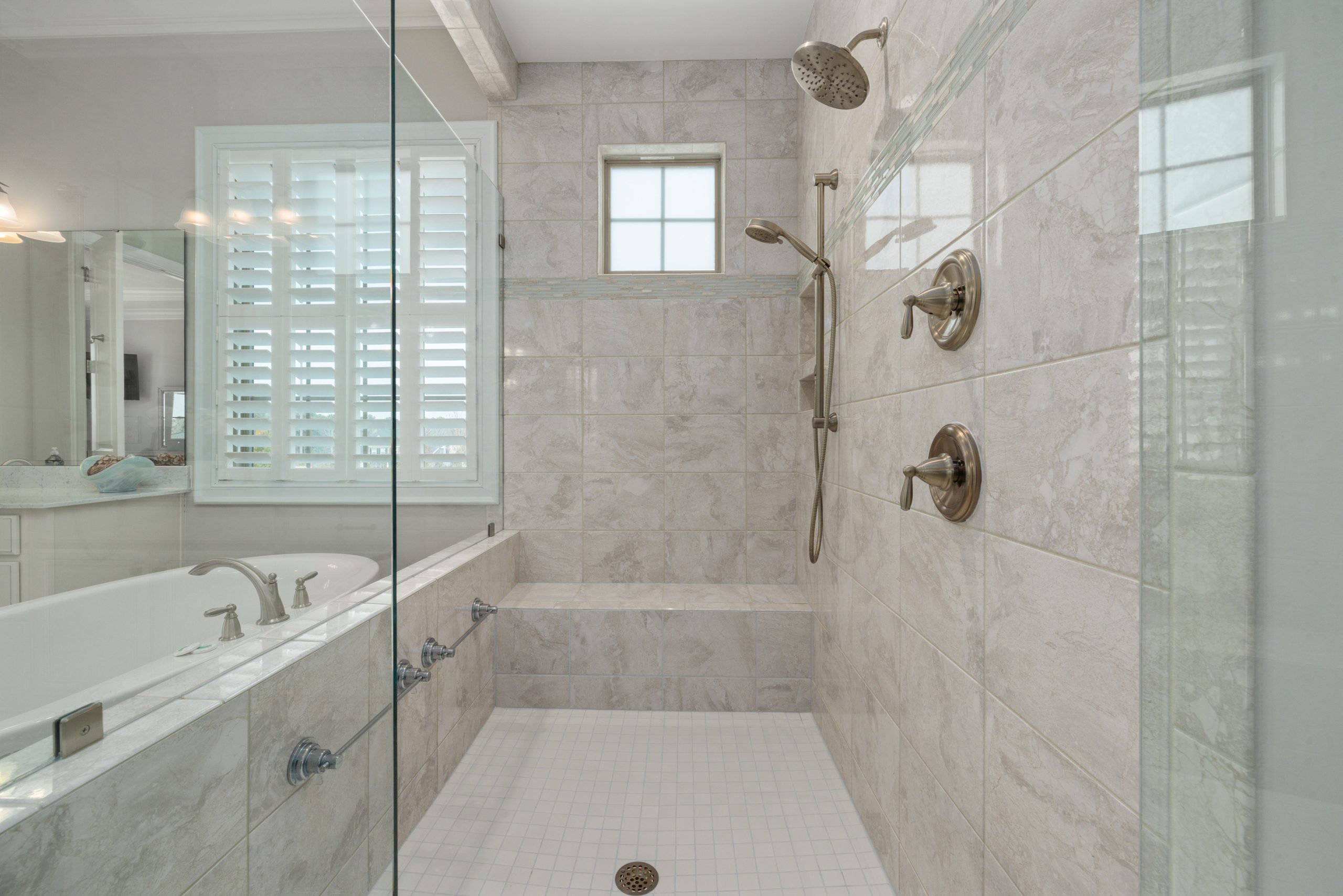 Modern bathroom interior showcasing a luxurious shower with white tiles and glass doors.