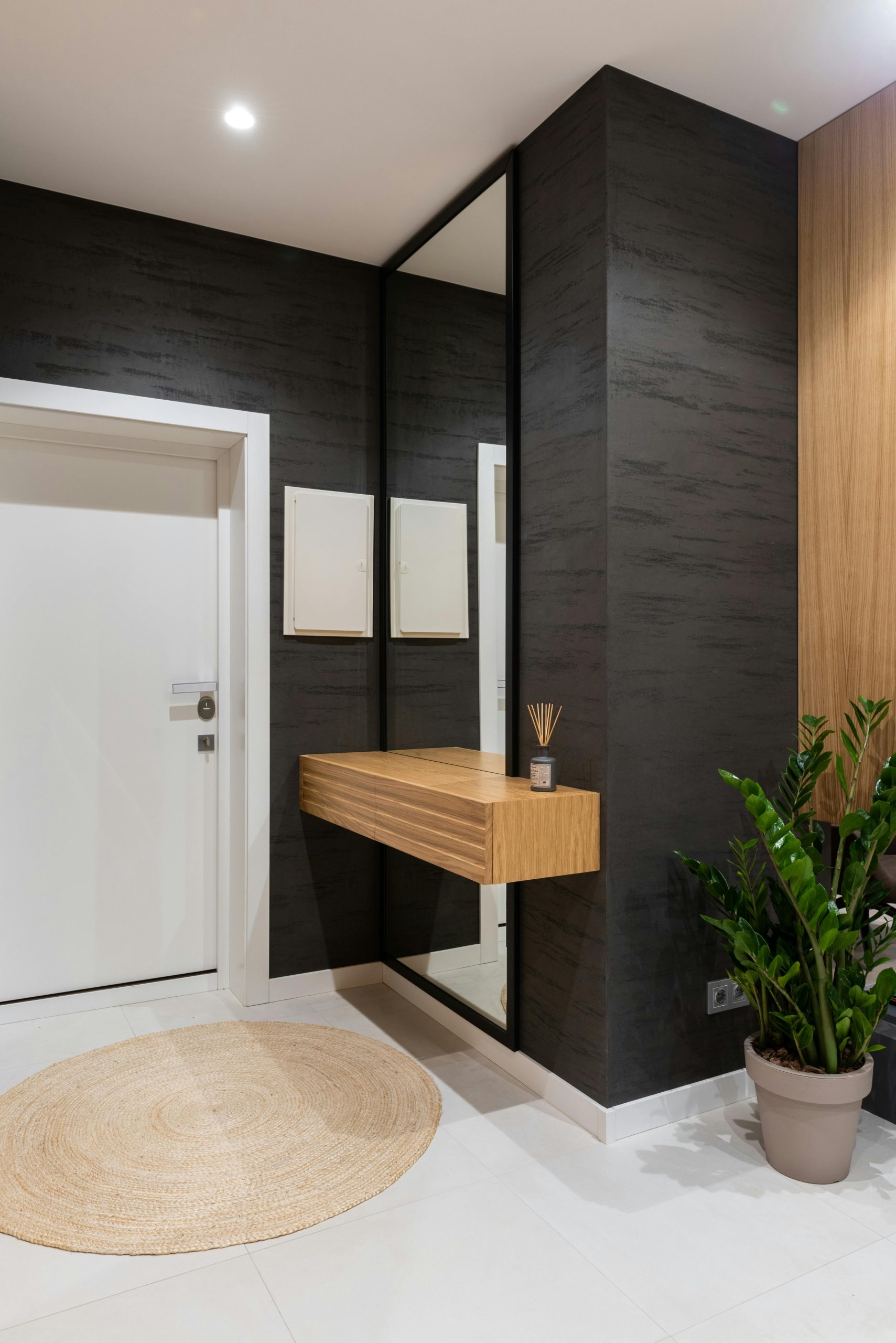 Modern bright flat interior with potted green plant placed in hallway near shelf and mirror next to door and carpet on floor
