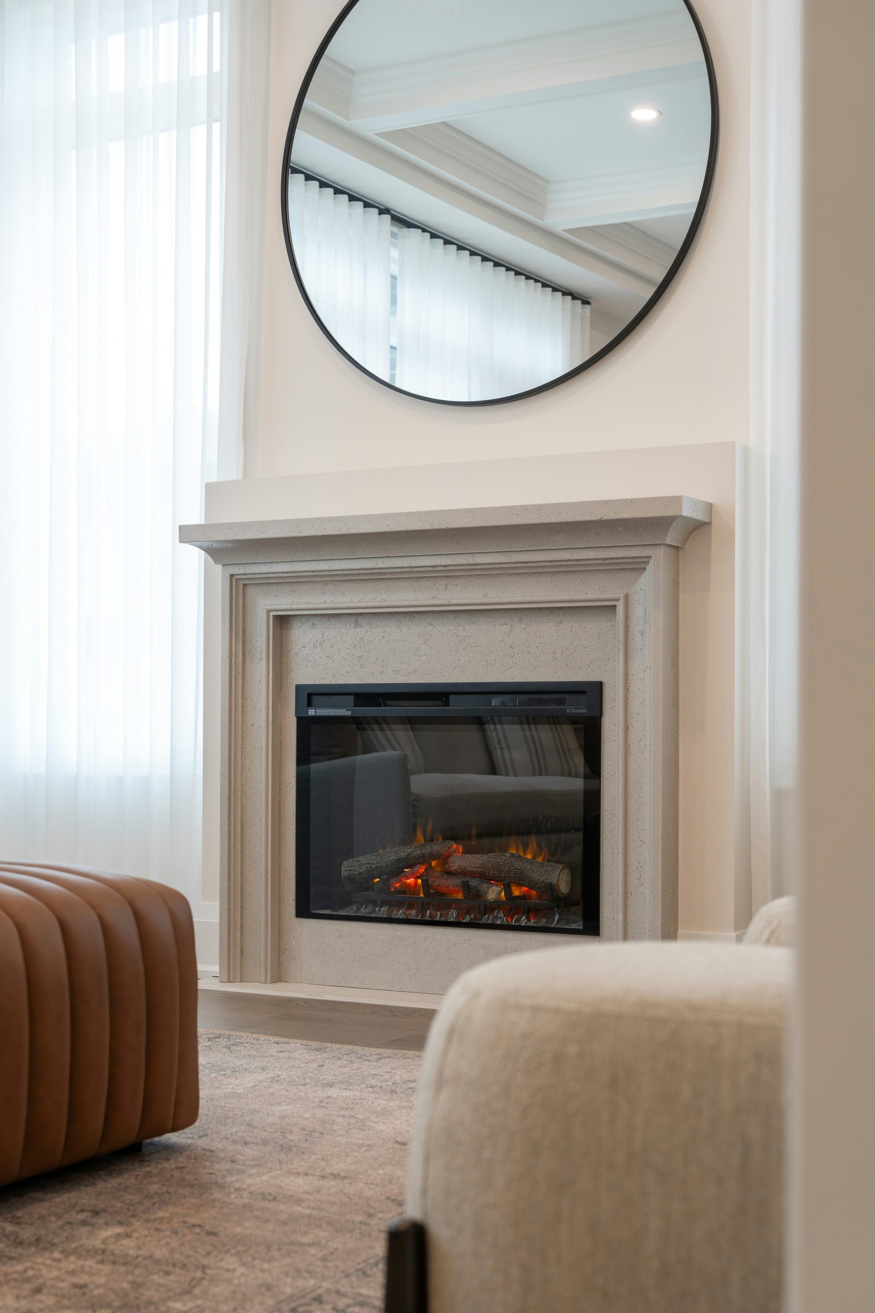 Modern fireplace with a large round mirror above.
