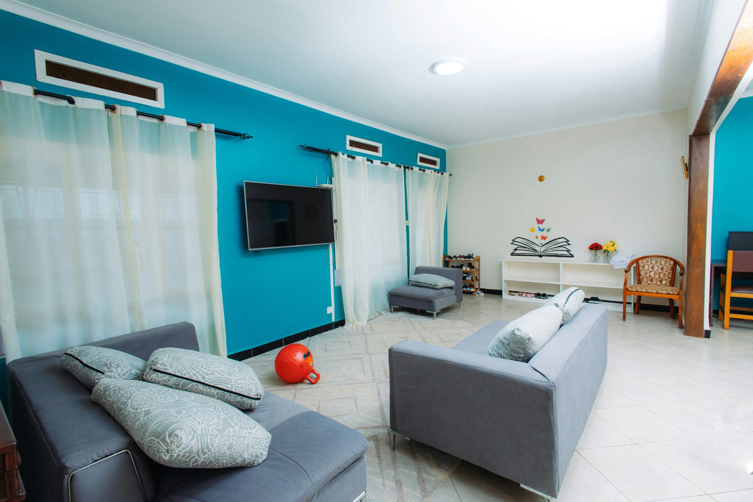 Modern living room with teal walls and gray sofas.