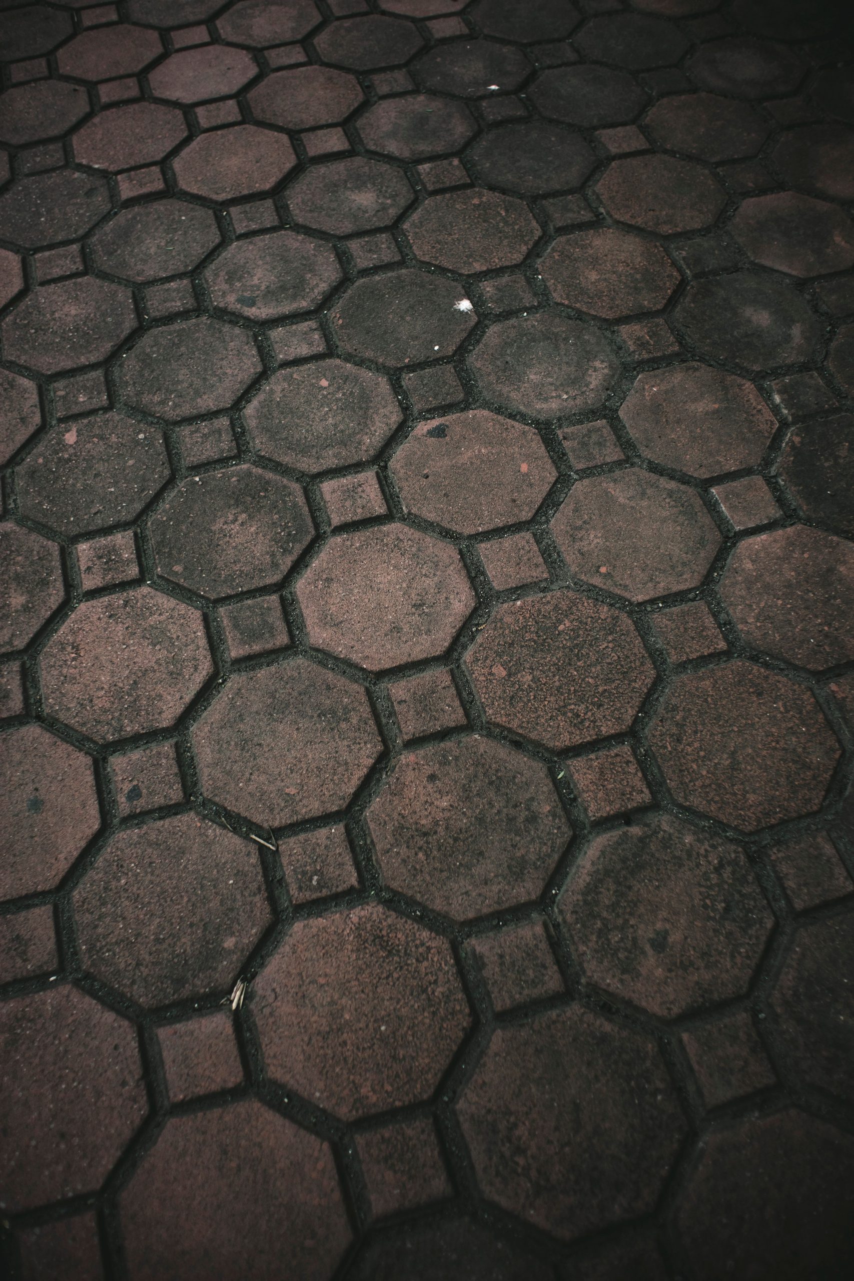 Moody geometric brown paver stones forming a hexagonal pattern outdoors.