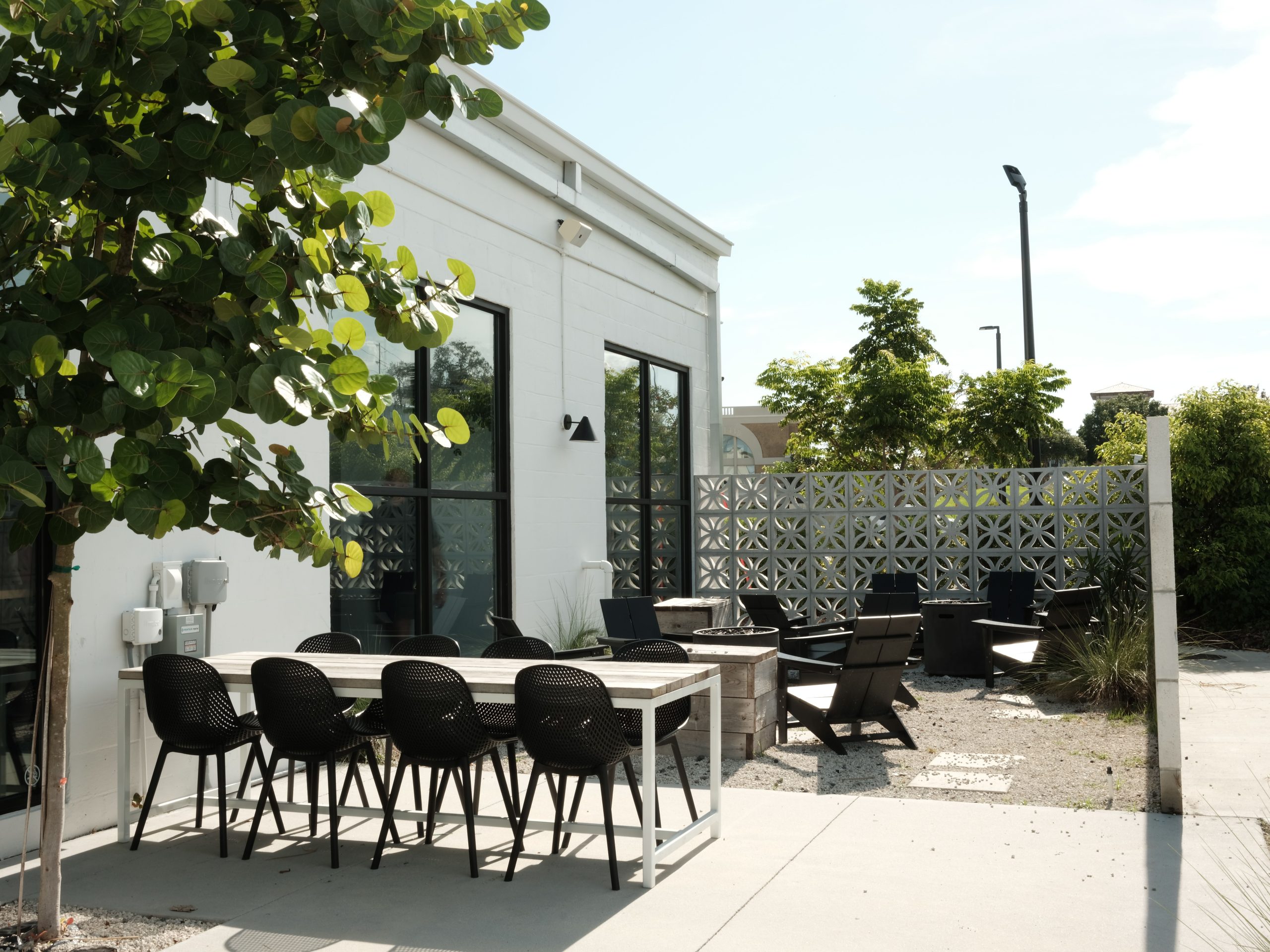 Outdoor dining area with black chairs and tables in a sunny garden setting, perfect for summer gatherings.