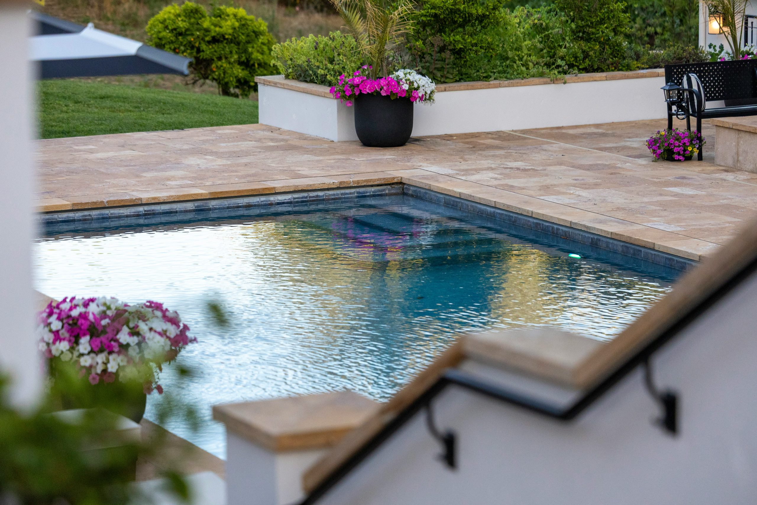 Outdoor swimming pool with surrounding patio and vibrant flowers.