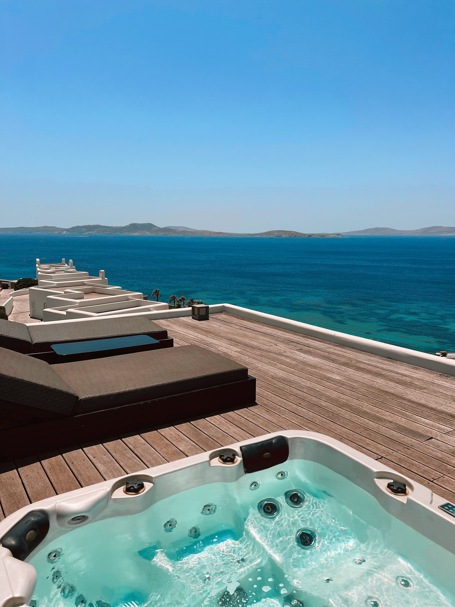 Relaxing jacuzzi on a wooden deck overlooking the beautiful blue ocean on a sunny day.