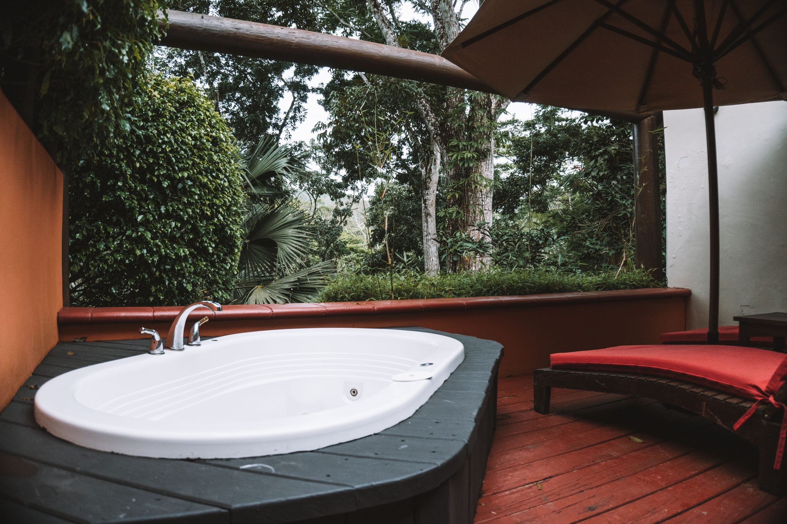 Relaxing outdoor jacuzzi on a luxury terrace surrounded by lush greenery and serene ambiance.