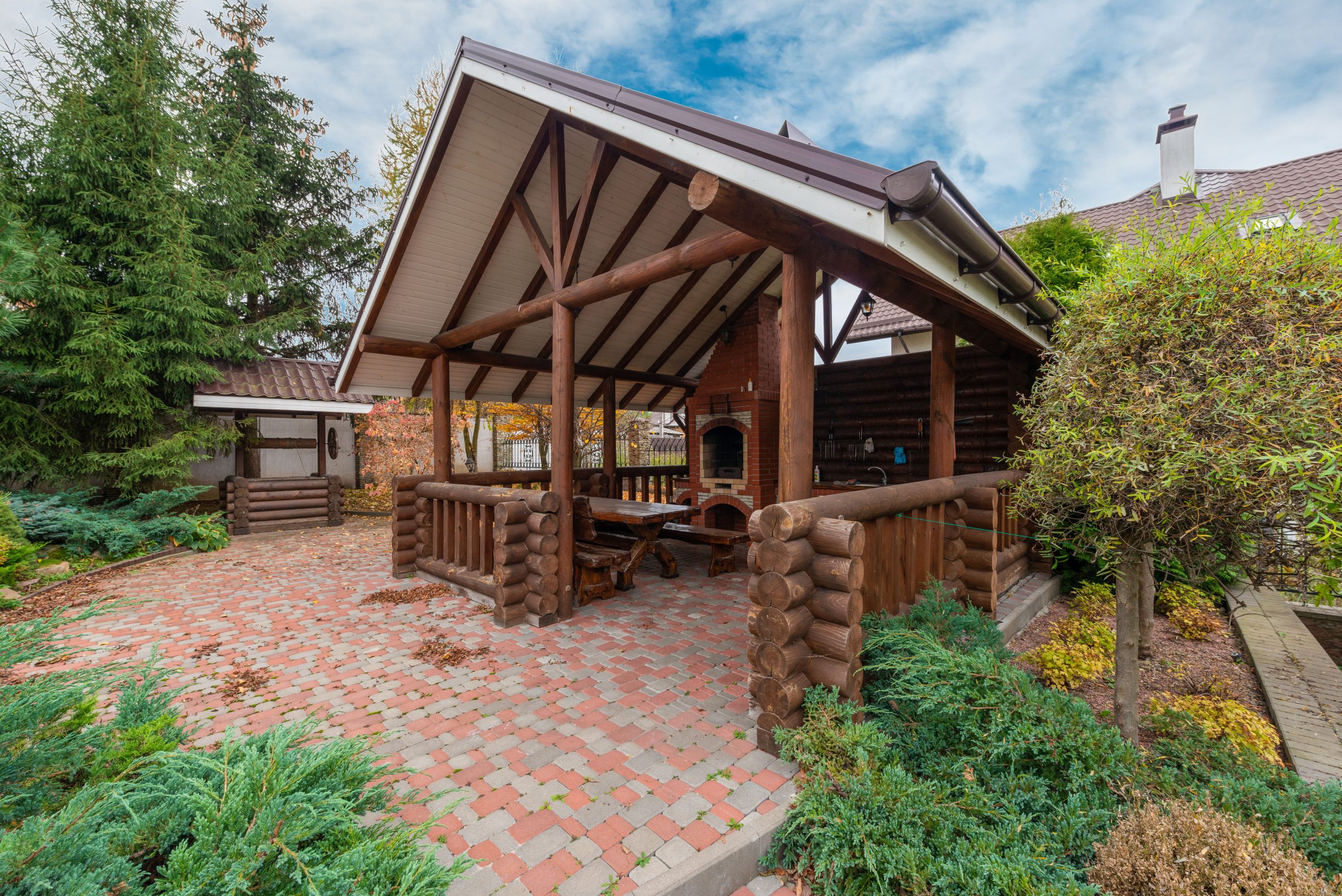 Rustic log pavilion in a garden setting, perfect for outdoor gatherings.