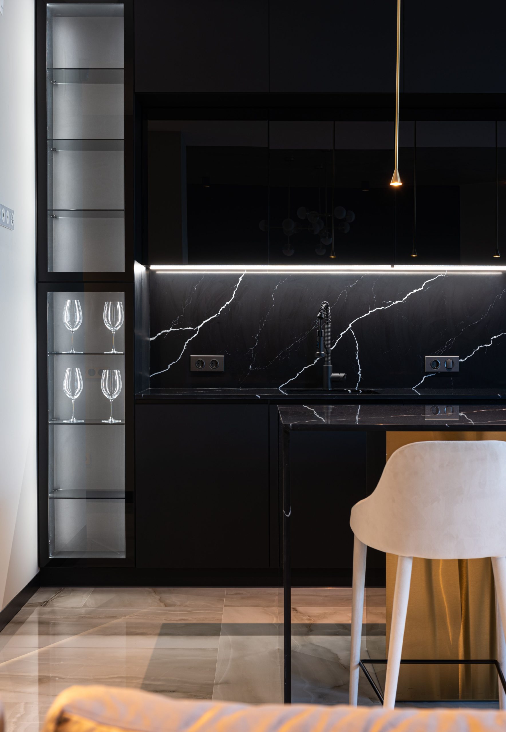 Sleek and stylish modern kitchen with black marble surfaces and elegant lighting.