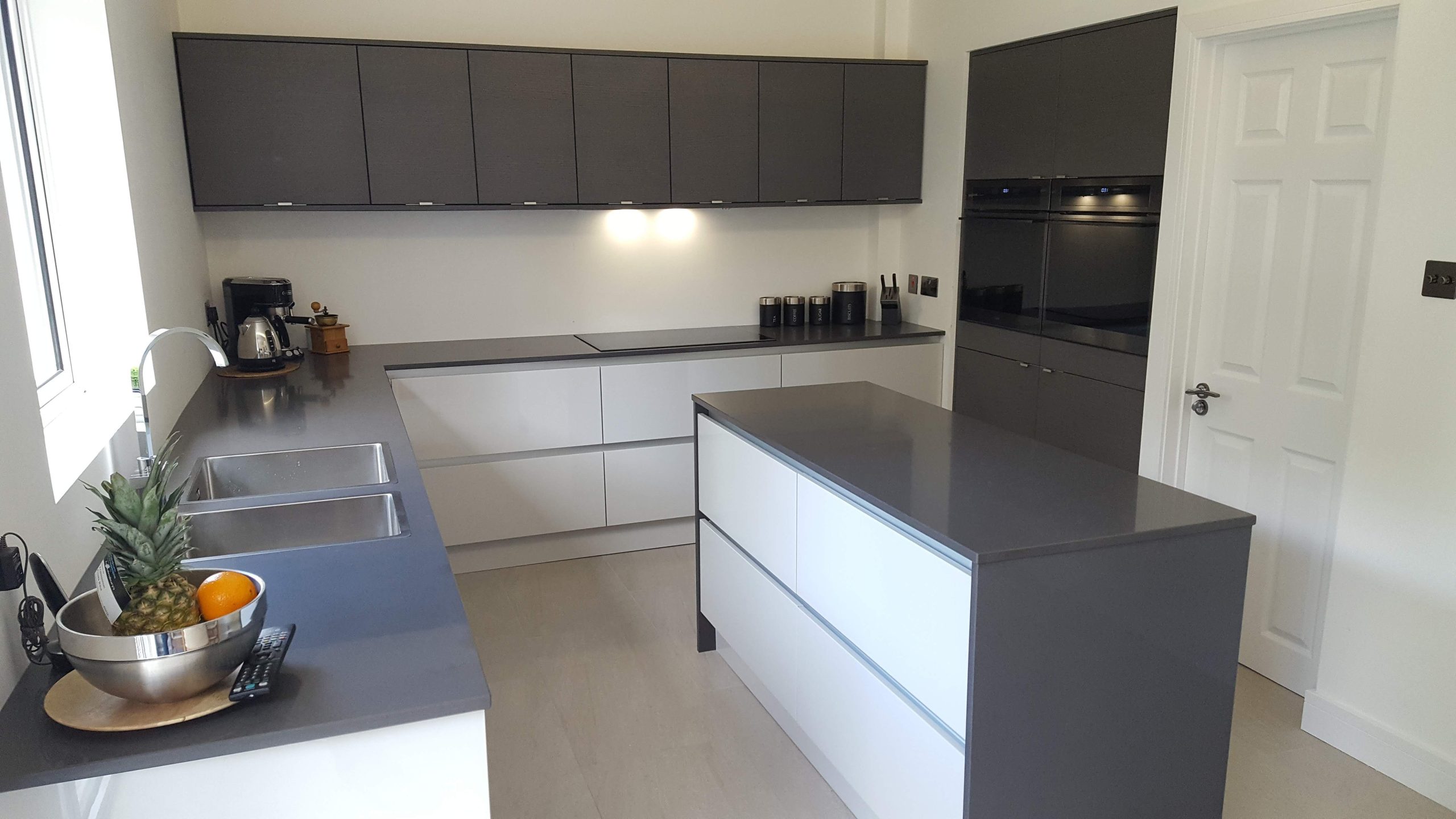 Sleek modern kitchen with dark cabinets, island, and elegant lighting.