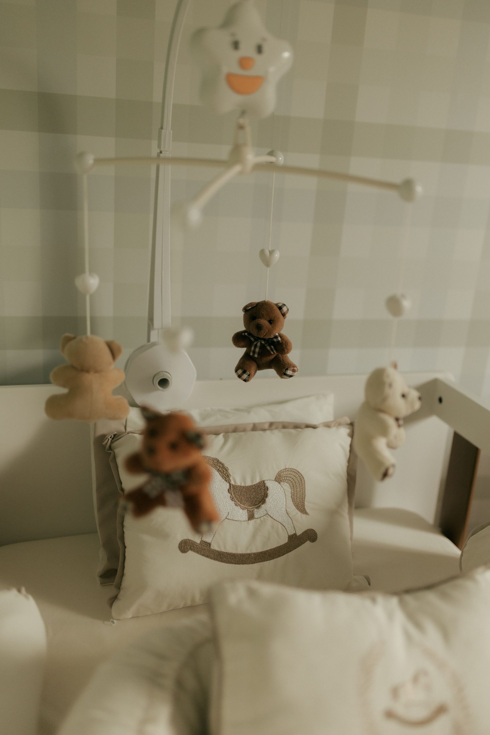 Soft and calming baby nursery featuring a teddy bear mobile above a crib, creating a peaceful environment.