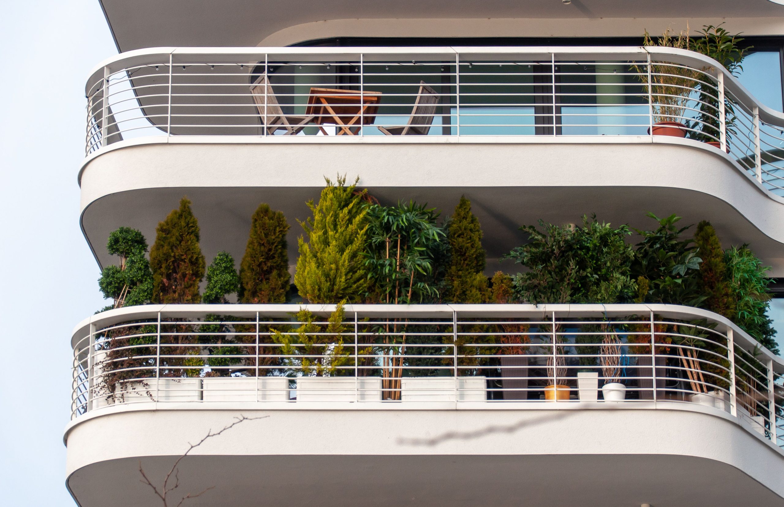 Sophisticated apartment balcony adorned with lush plants and stylish furniture, showcasing modern living.