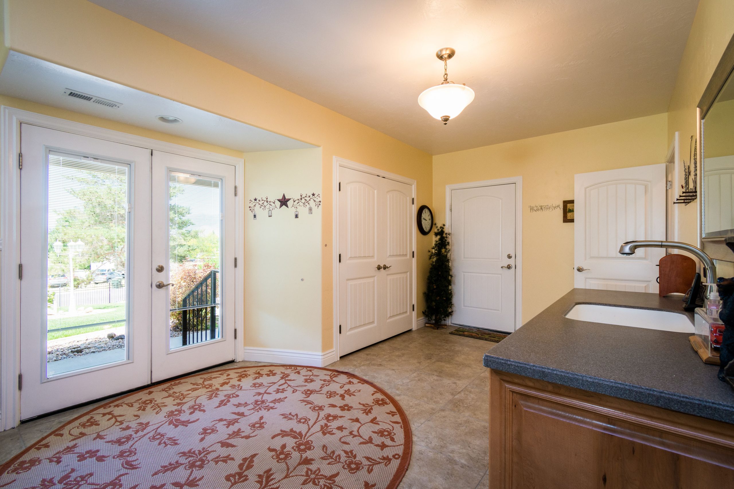 Spacious and bright entryway featuring a decorative rug and glass doors.