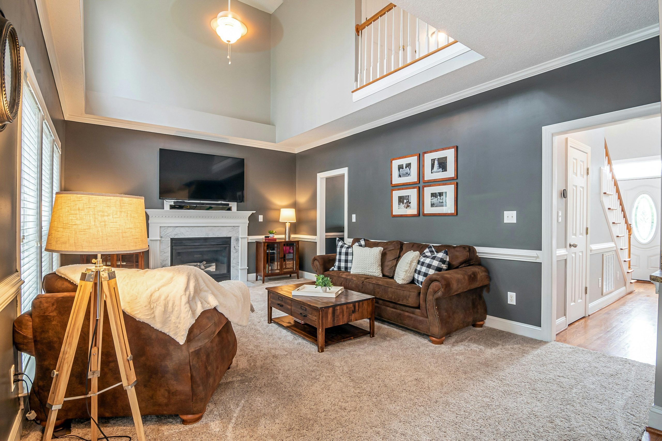 Spacious and elegant living room featuring a cozy fireplace, modern furniture, and warm lighting.