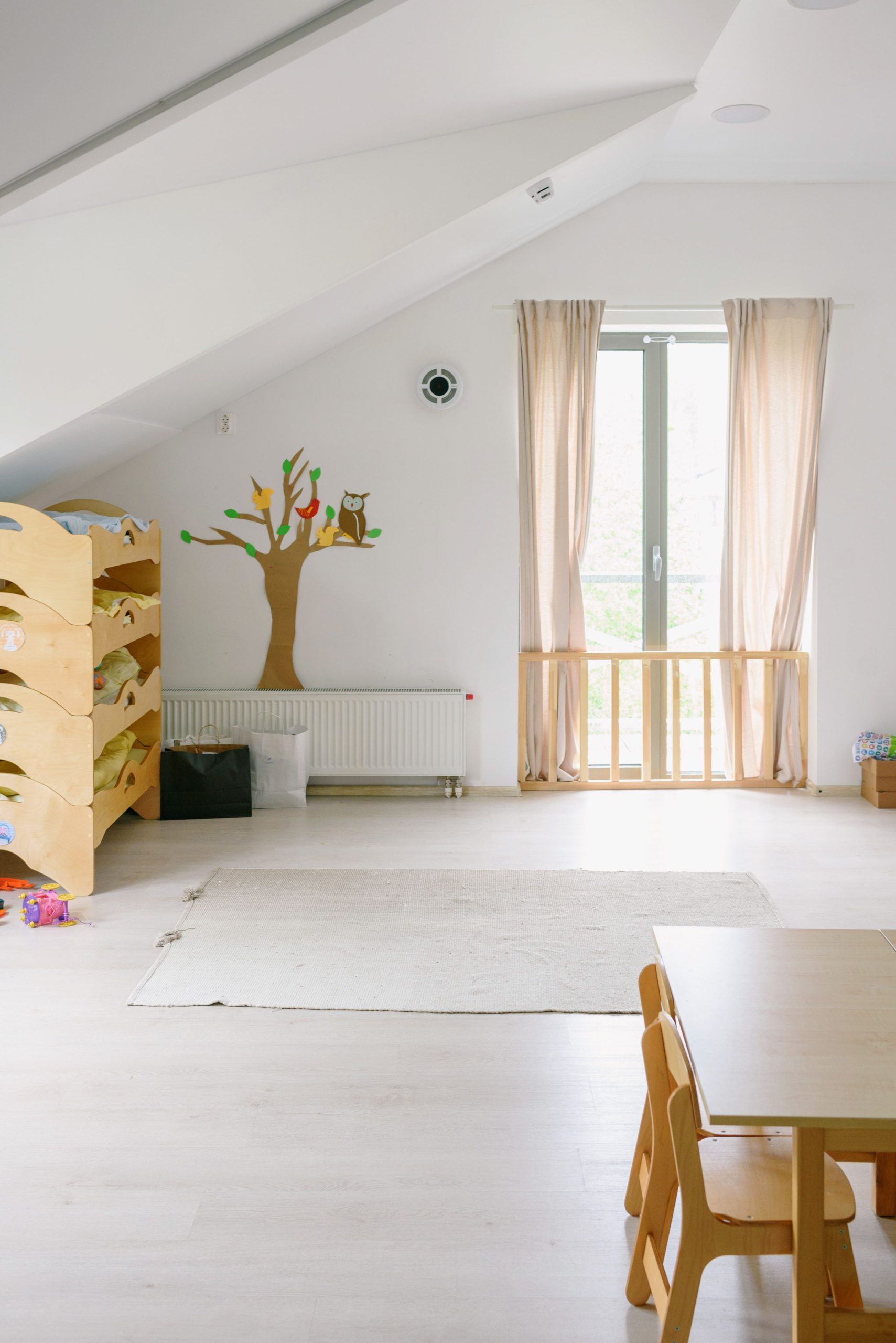Spacious contemporary children's room with wooden furniture and pastel tones, ideal for play and relaxation.