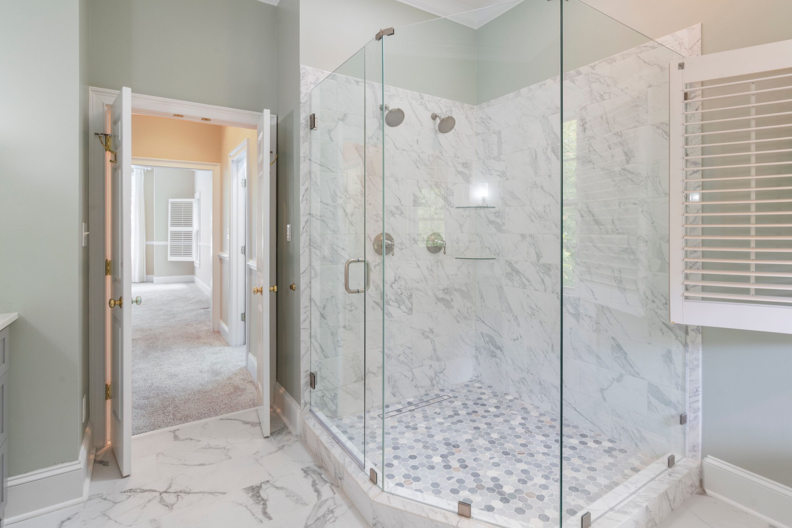Spacious luxury bathroom featuring a contemporary marble shower with glass doors and elegant interior design.