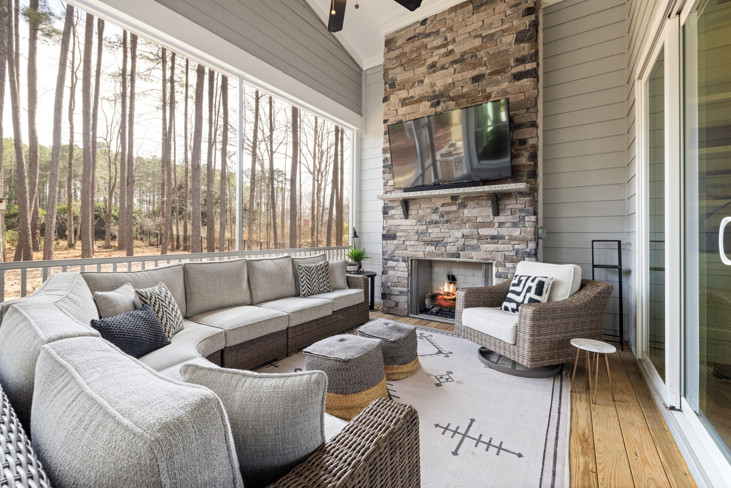 Spacious outdoor patio featuring a stone fireplace, modern furniture, and serene forest view.
