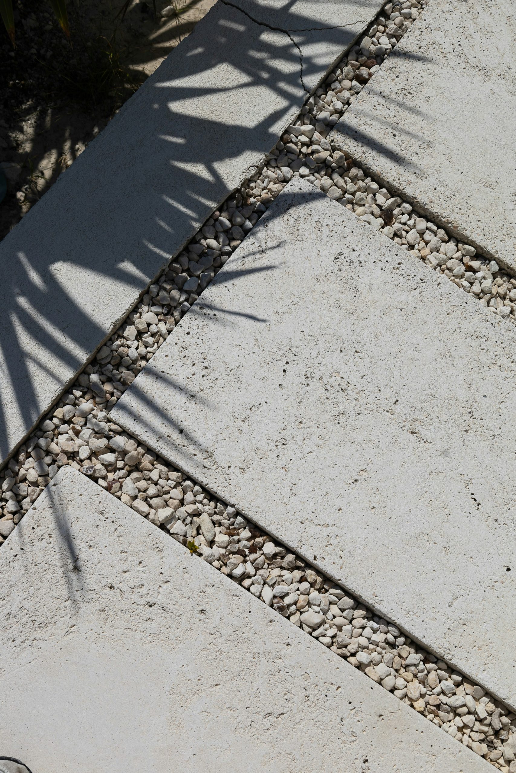 Stone pathway with decorative gravel and leaf shadows.