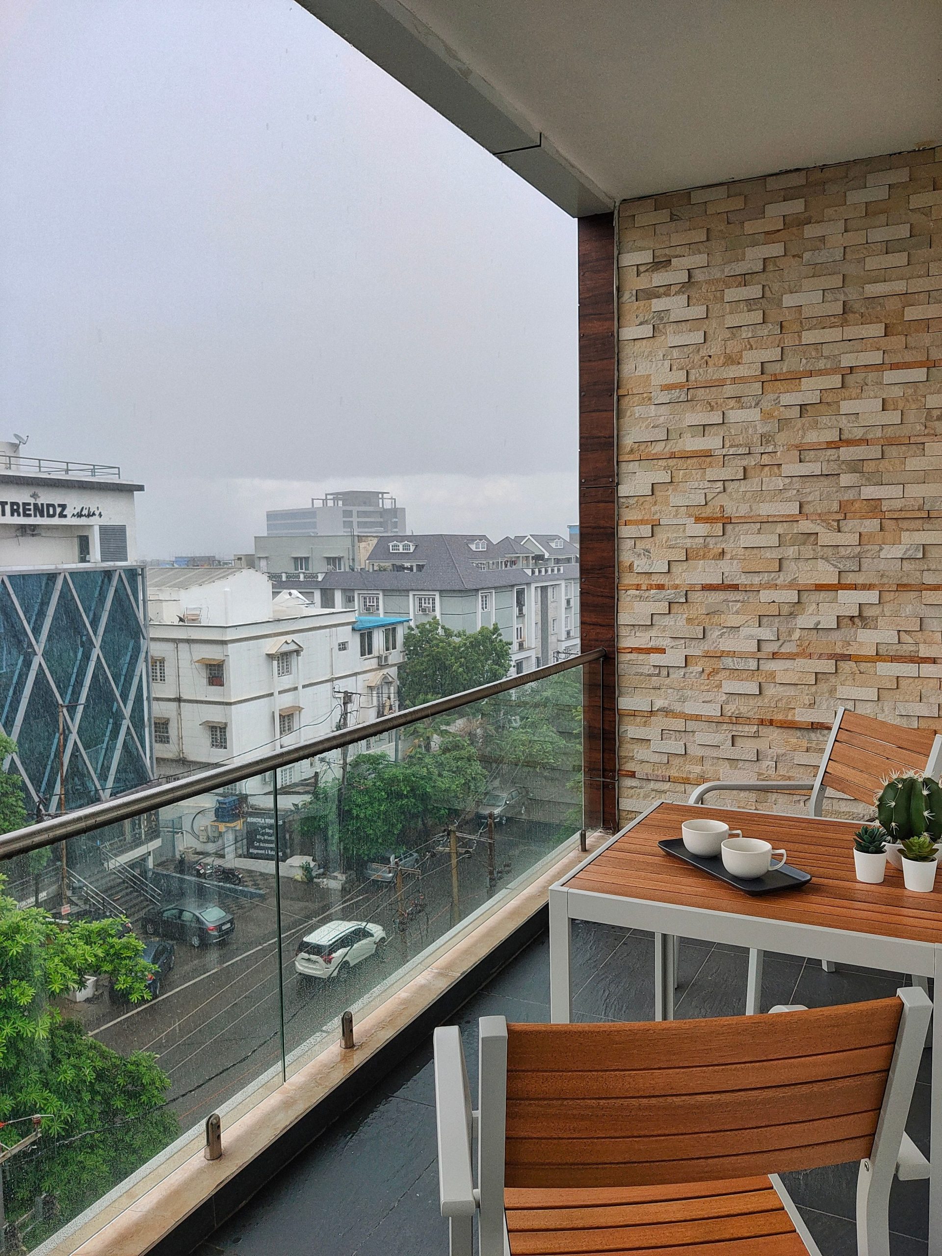 Stylish balcony with wooden furniture and city view, ideal for relaxation.