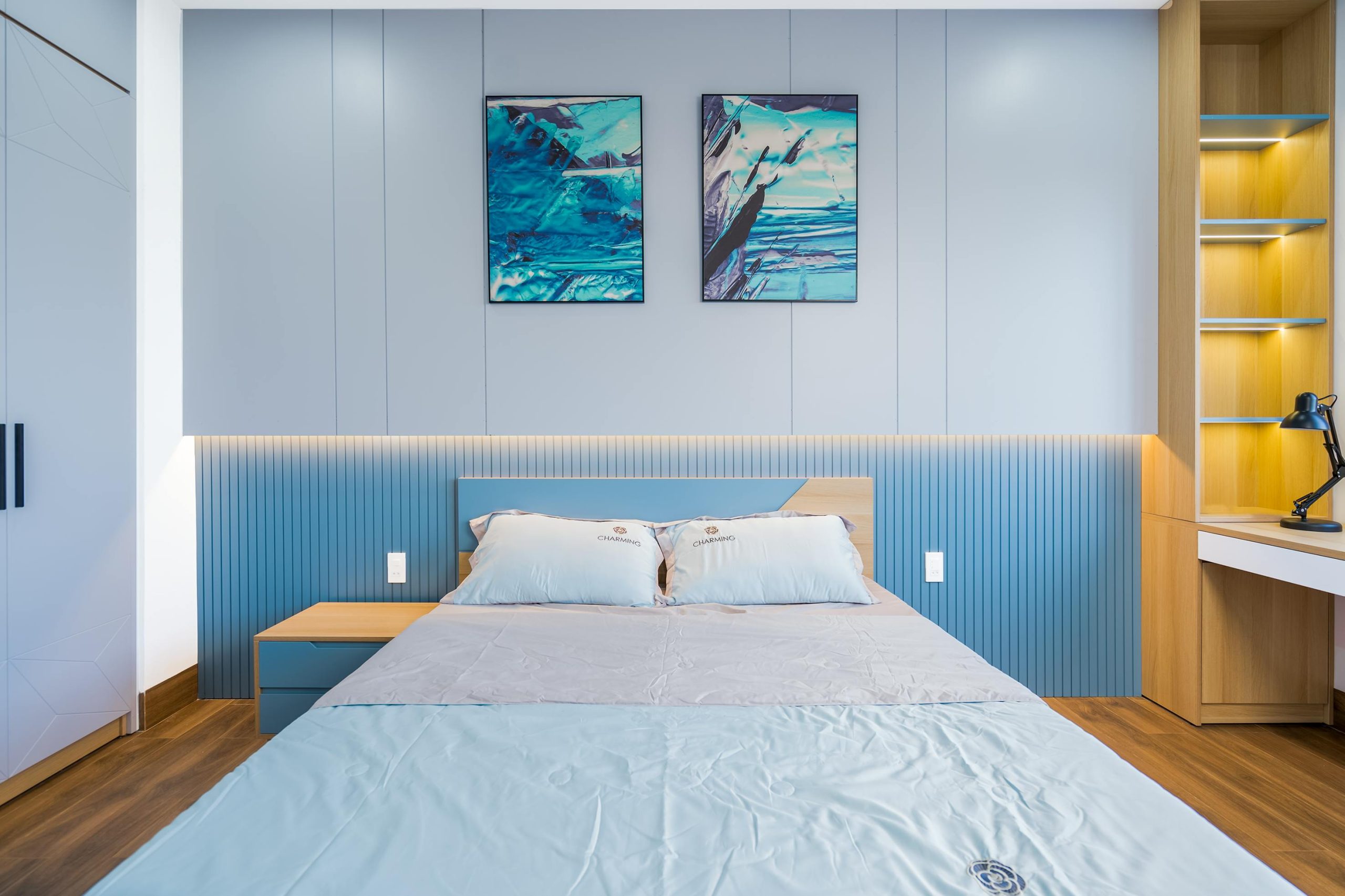 Stylish bedroom with blue decor, modern furnishings, and artistic wall art.