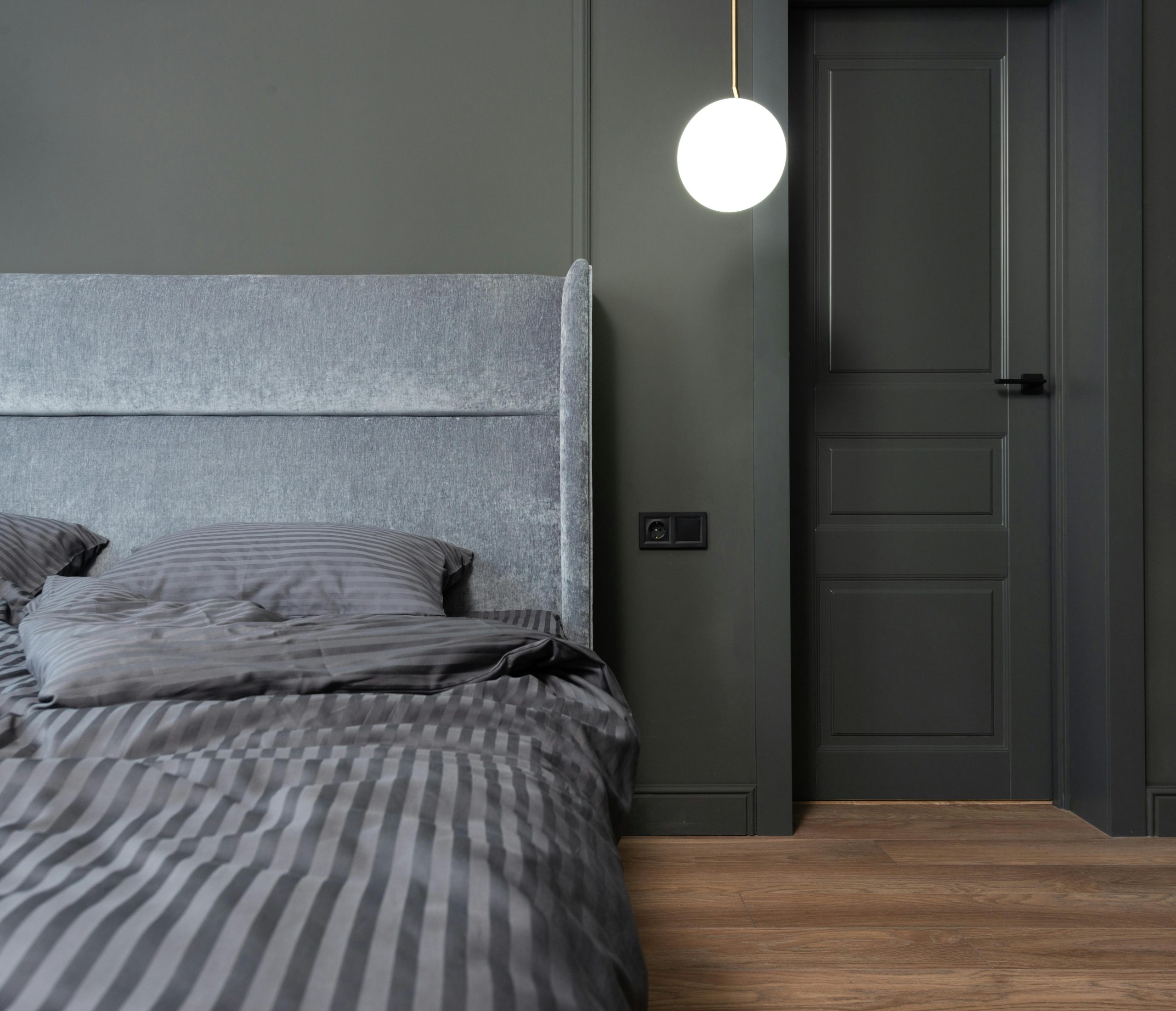 Stylish gray bedroom interior with modern lighting, emphasizing sleek design and comfort.