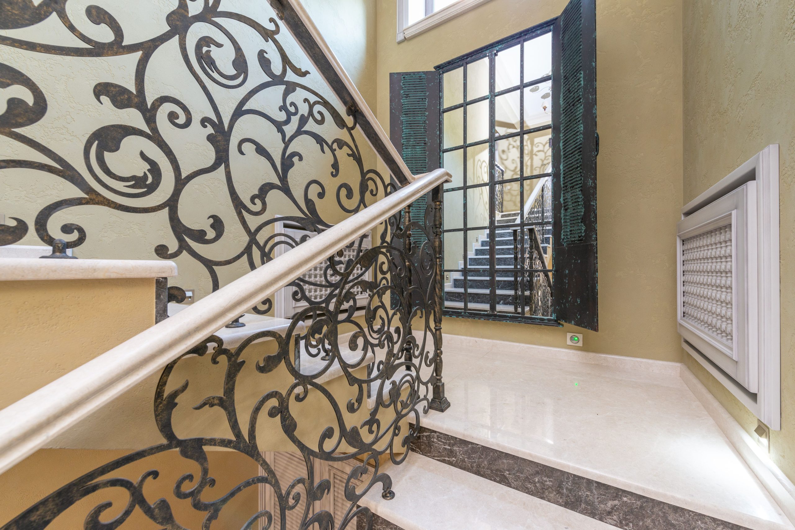Stylish indoor staircase featuring ornate wrought iron railings and a marble step design.