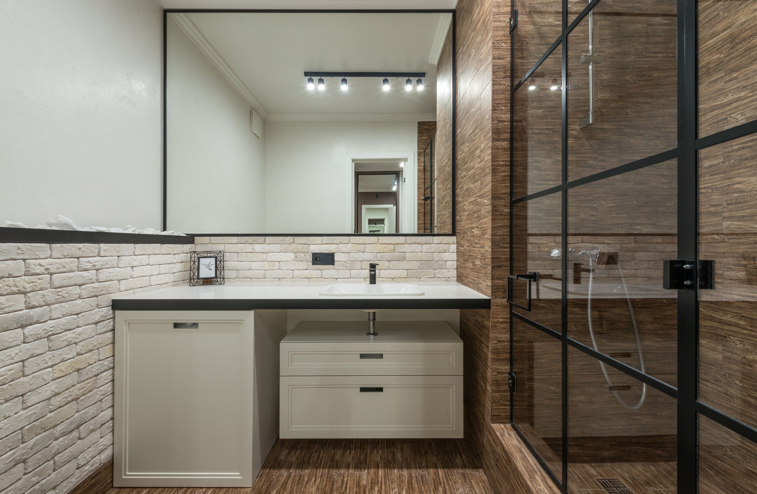 Stylish interior design of modern bathroom with white furniture and sink and shower cabin with glass door