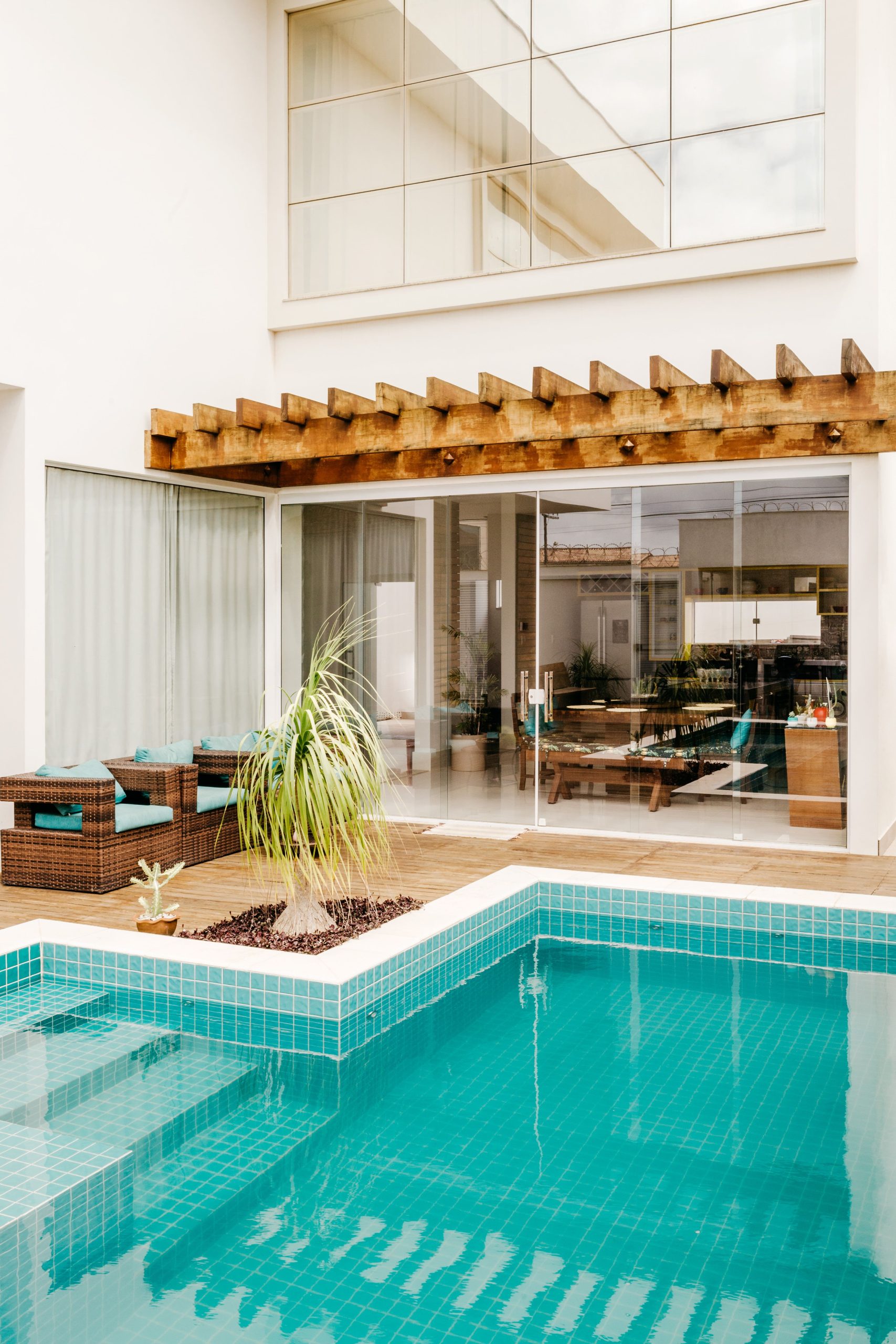 Stylish outdoor patio featuring a pool and modern architecture with glass doors and wooden pergola.