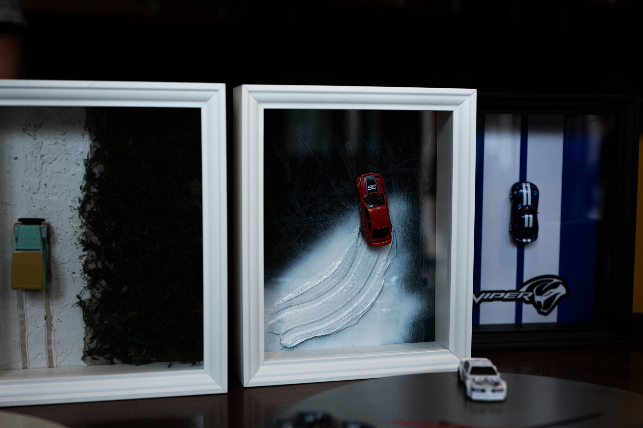 Toy cars displayed in three decorative frames.