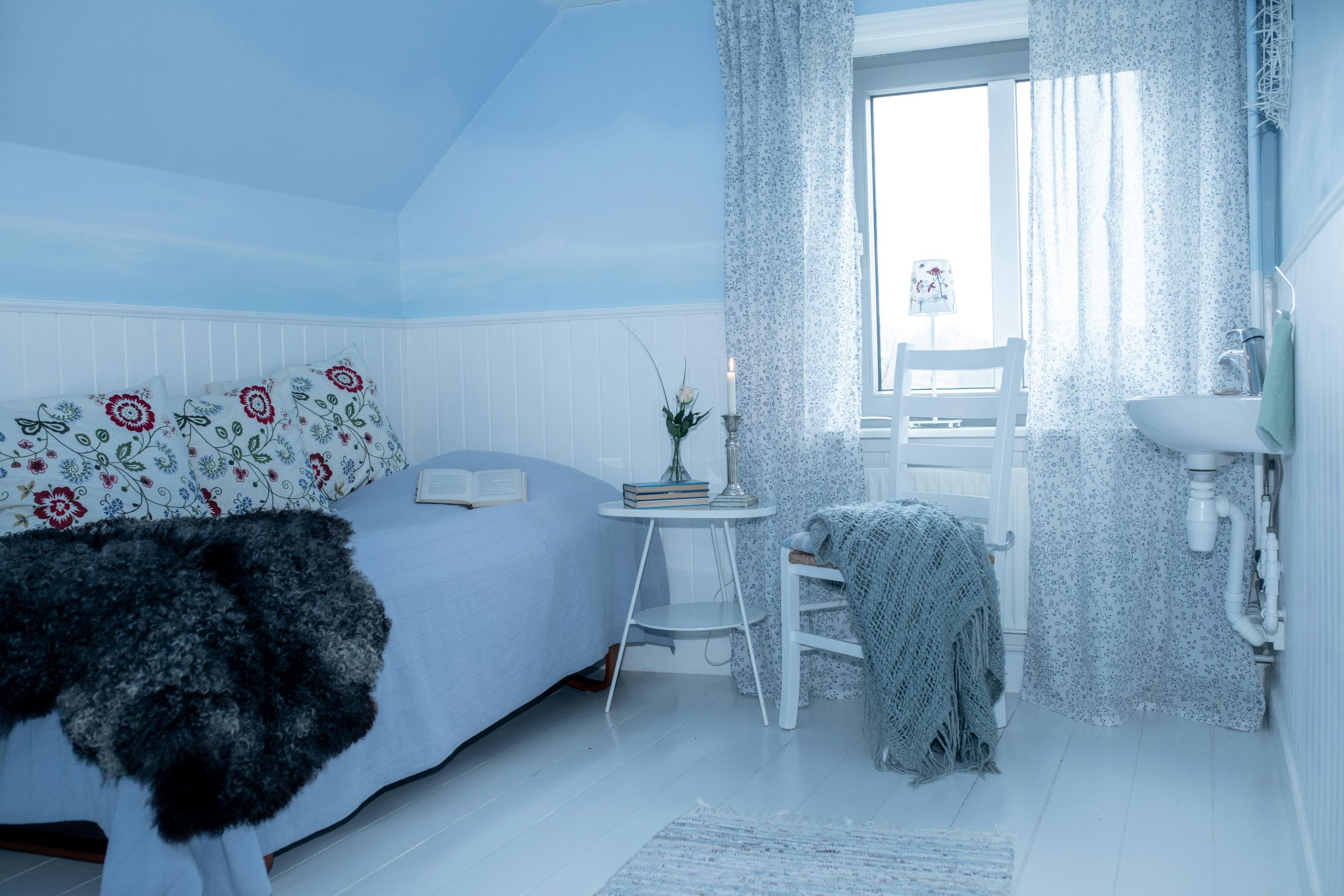 Tranquil and minimalist bedroom interior featuring a blue theme with cozy elements and natural light.