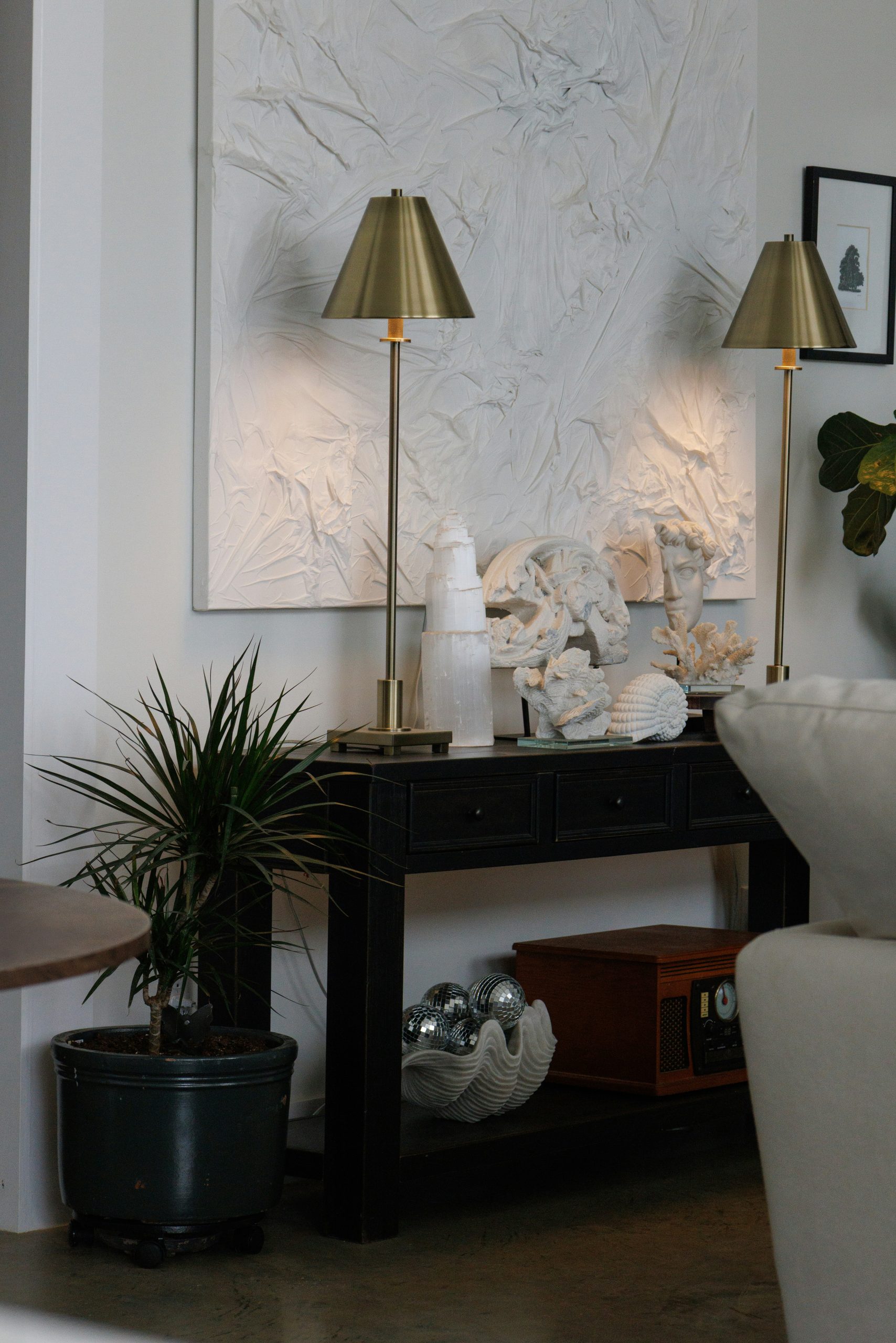 Two brass lamps on a black console table.