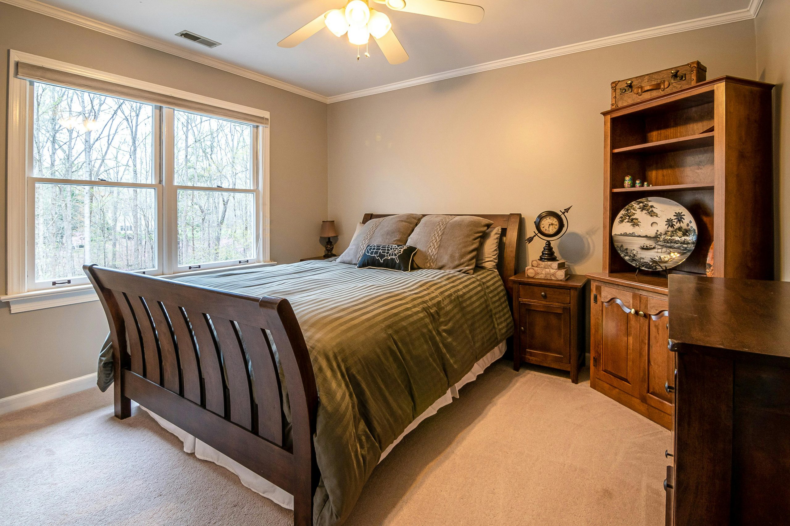Warm and cozy bedroom interior featuring a wooden bed frame and furniture, with a large window view.
