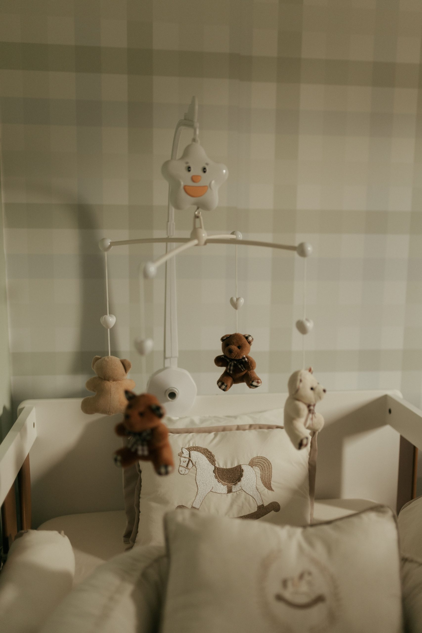 Warm, inviting baby nursery with plush teddy bear mobile above crib, creating a soothing environment.