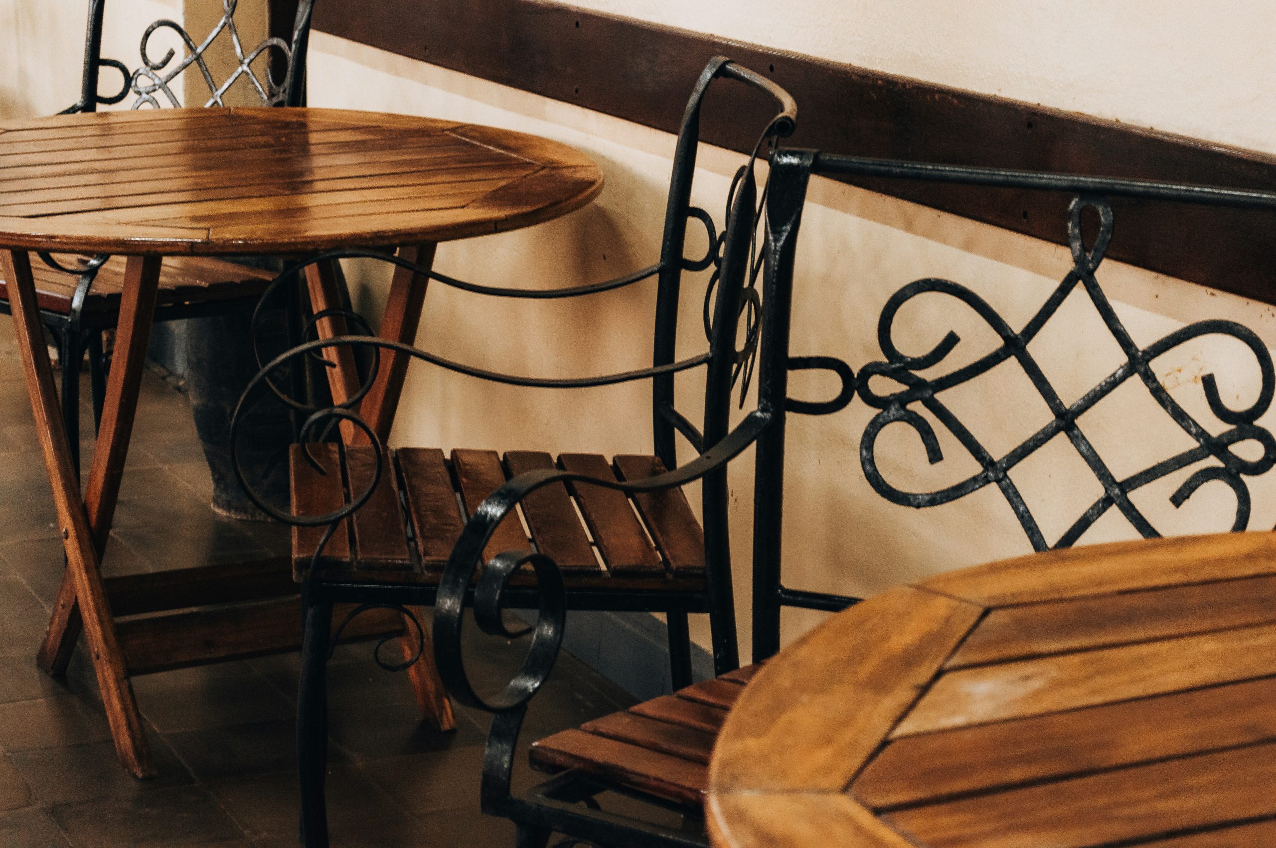 Wooden tables and ornate chairs at an outdoor cafe.